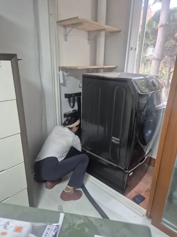 베란다 세탁기 옆 좁은 공간에서 하부를 확인하는 모습